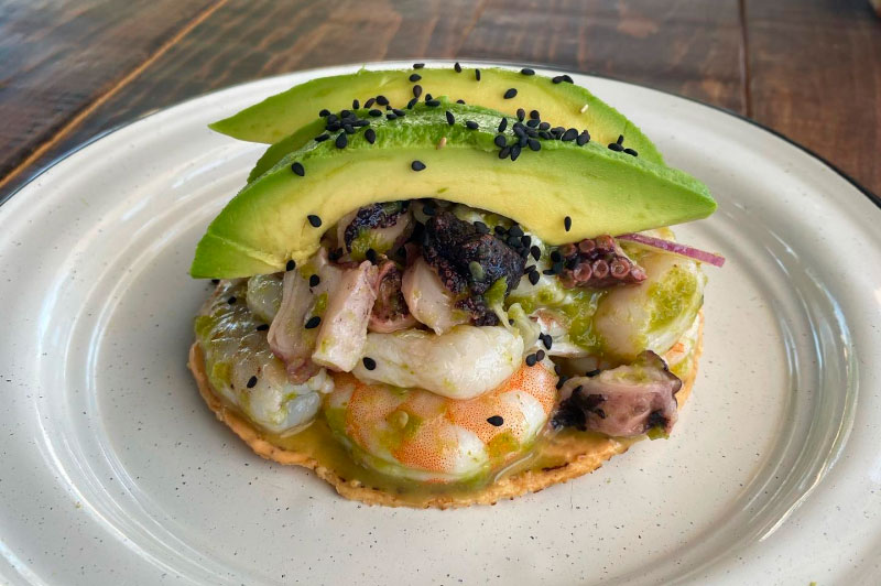 Tostada de camarón, callo y pulpo en base de alioli chiplotle con aguacate en La Barracuda